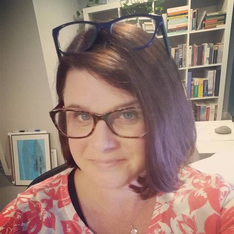 Photo of white woman with brown hair and glasses, with a second pair of glasses perched on her head